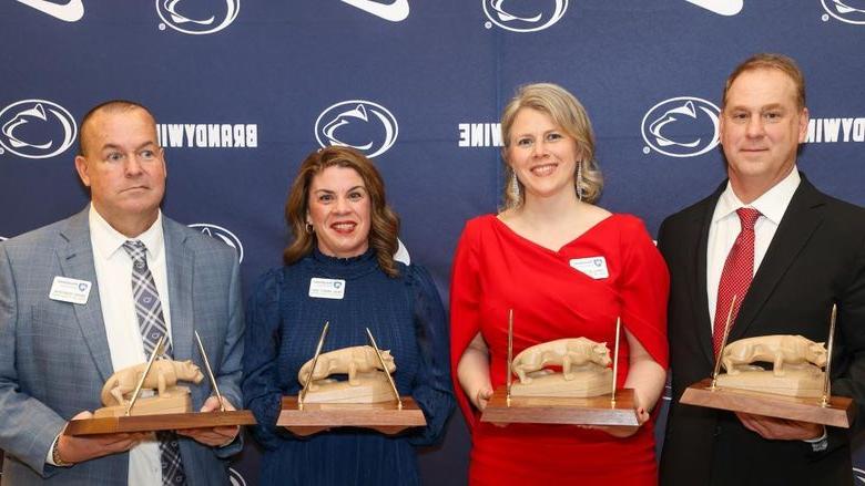 four people holding awards